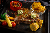 Szárazon érlelt T-bone steak (500~600g) chilis babbal, hullámos sült burgonya szeletekkel, grillezett kukoricával és fűszervajjalt (az ár 100g-ra vonatkozik) -